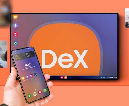 A hand holding a Samsung phone, with a background screen displaying DeX mode.