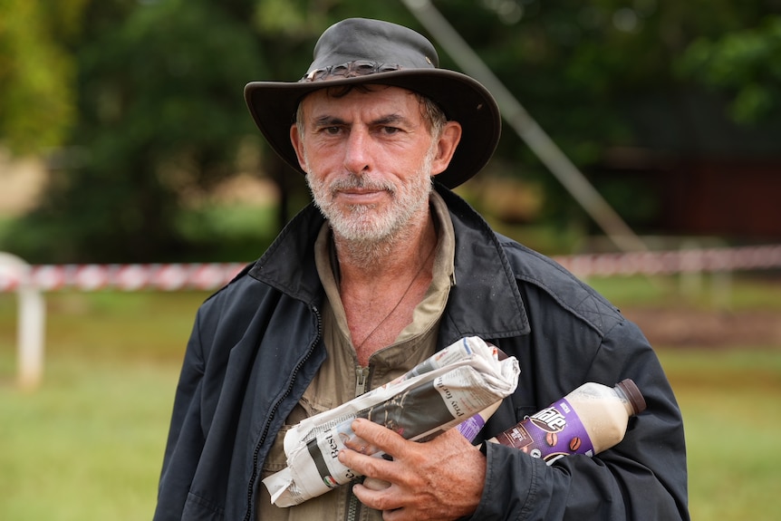 A man in wet weather gear holding a newspaper