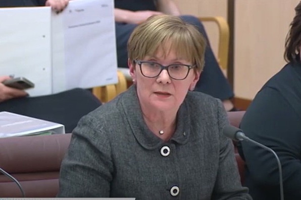 A middle-aged woman with short, fair hair at a senate estimates hearing.