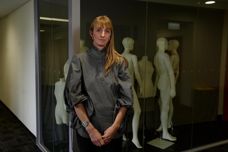 Dr Harriette Richards looks at the camera in front of a room of mannequins