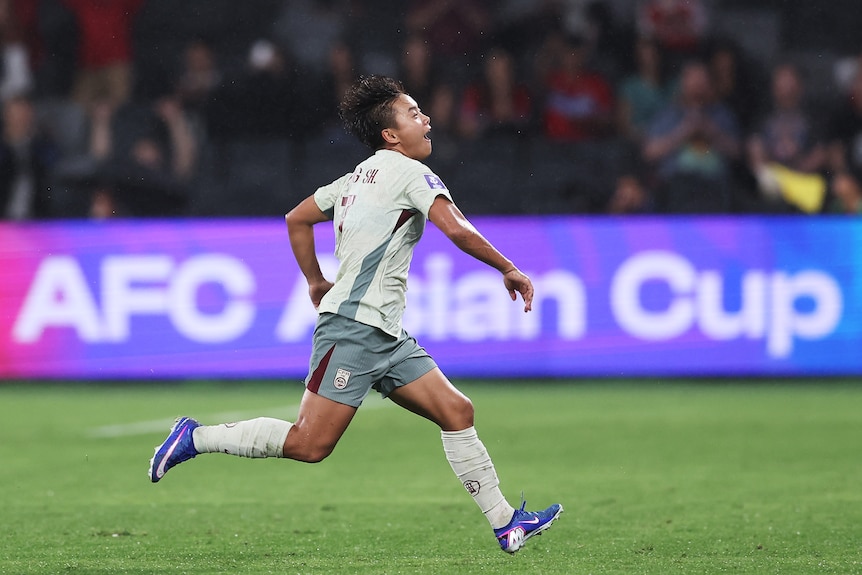 A soccer player in white celebrates a goal