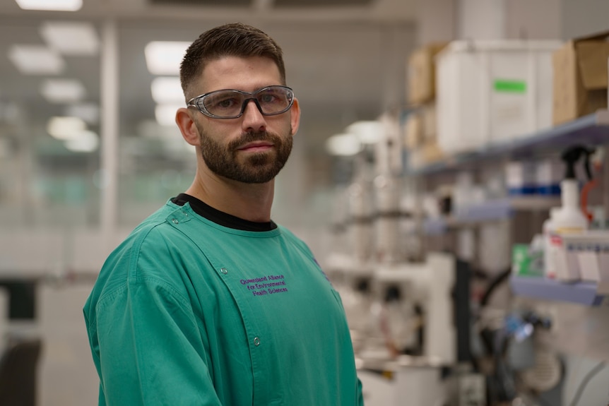 Dr Timothy Piatkowski stands in a hospital corridor wearing green scrubs.