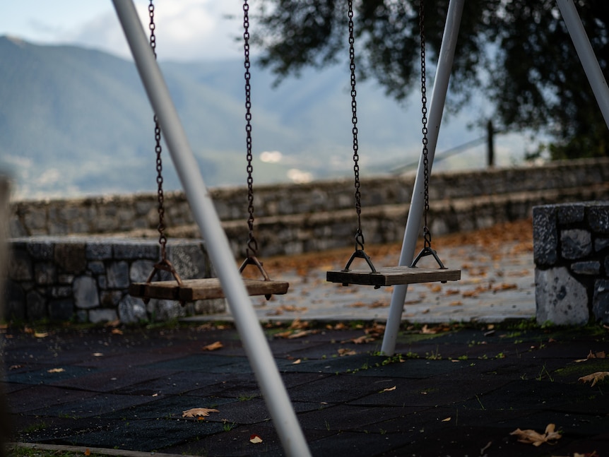 A set of child swings in a playground.
