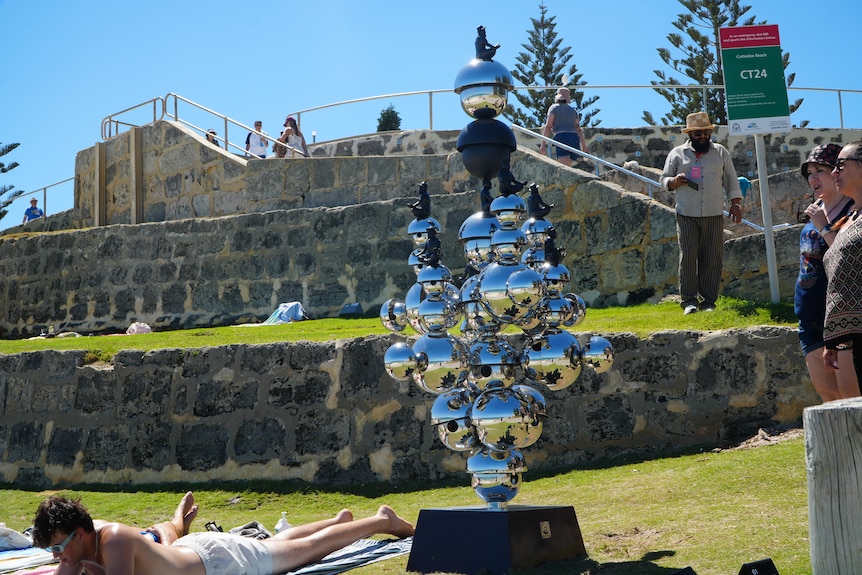 Art pieces installed at a beach as people lay sunbaking