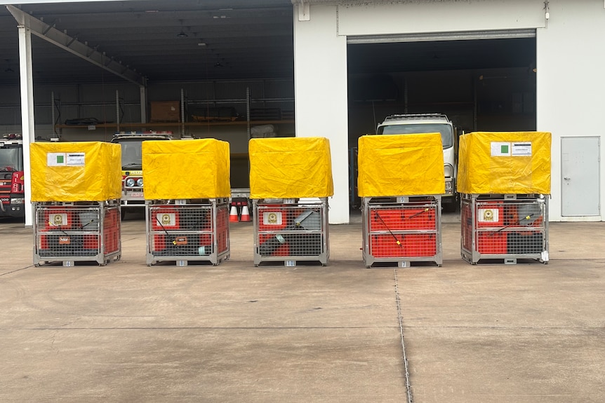 Crates with equipment in them with yellow tarps on top.