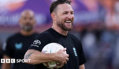 Brendon McCullum smiles with a football under his arm