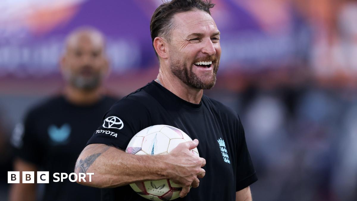 Brendon McCullum smiles with a football under his arm