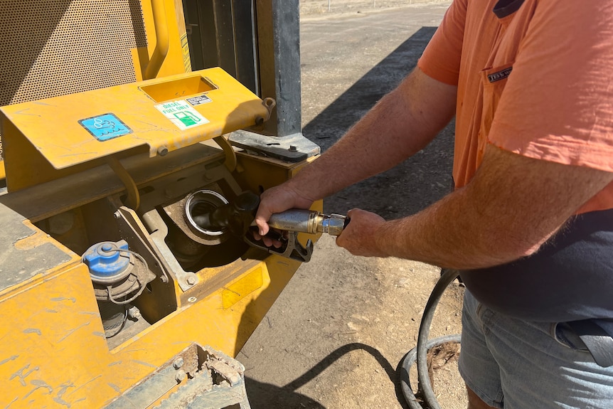 Fuel being pumped into a tractor by a man. 