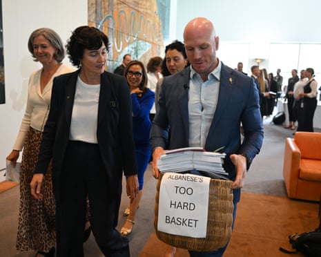 Independent Senator David Pocock carries a basket named ‘Albanese’s too hard basket’ full of government reports after a press conference.