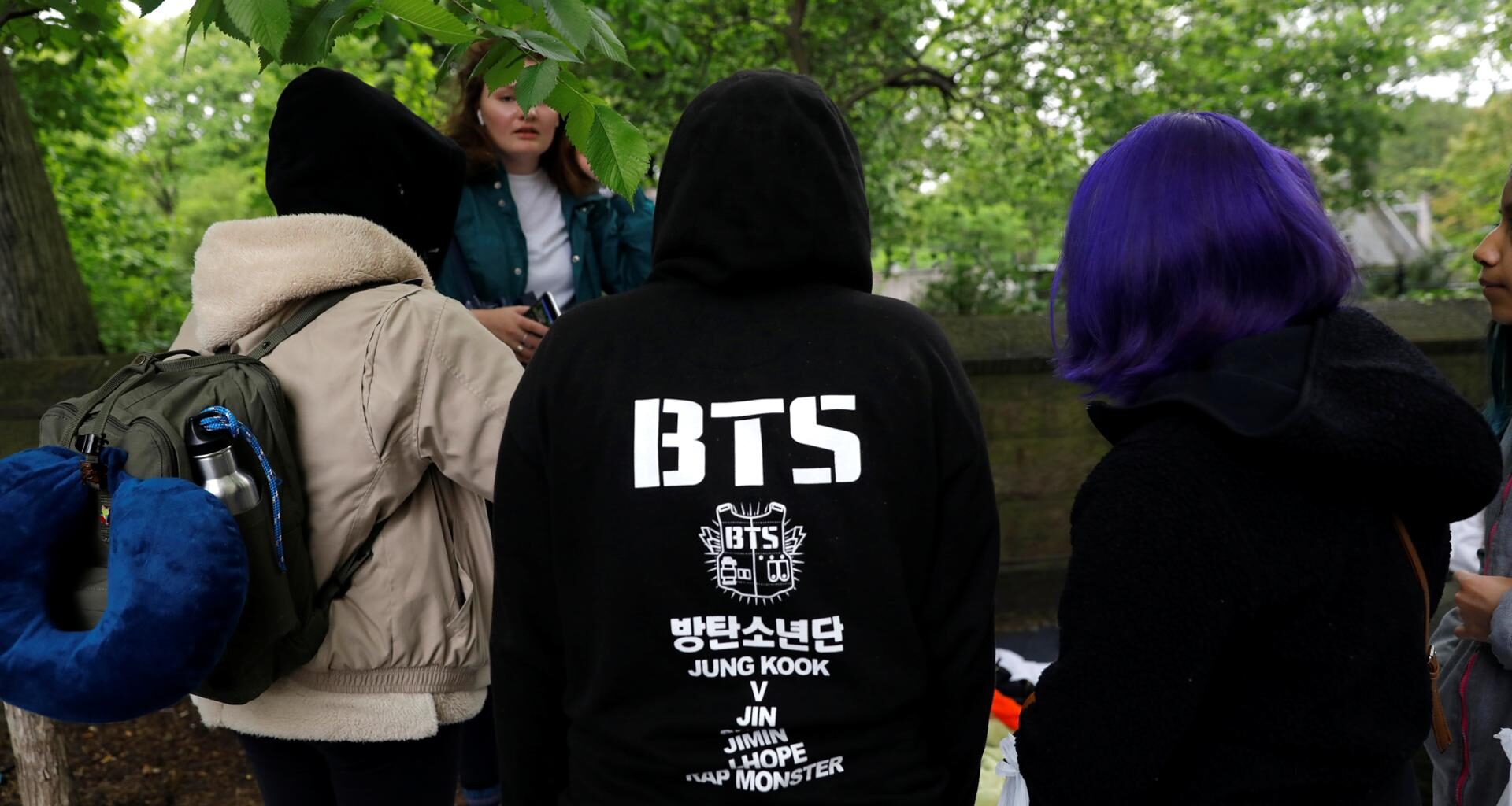 Fans of the K-Pop boy group BTS wait in the rain outside Central Park a day ahead of BTS