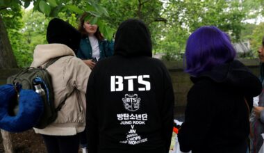 Fans of the K-Pop boy group BTS wait in the rain outside Central Park a day ahead of BTS