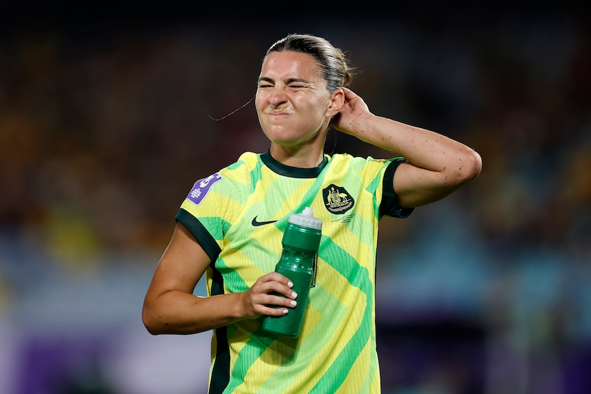 Steph Catley scratches her head with her left hand