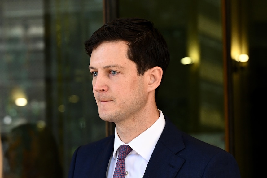 A man with dark hair wearing a suit and tie