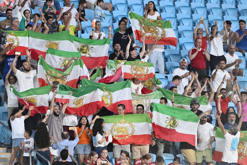 Football fans hold the Iranian 'lion and sun' flag in the stands of a Women's Asian Cup game