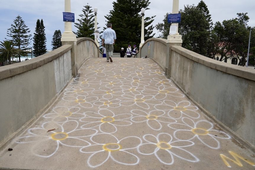White and yellow flowers painted on the bridge the Bondi shooters fired from.