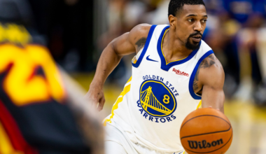A basketball player in a Golden State Warriors jersey dribbles a Wilson basketball, looking intently to his right during a game.