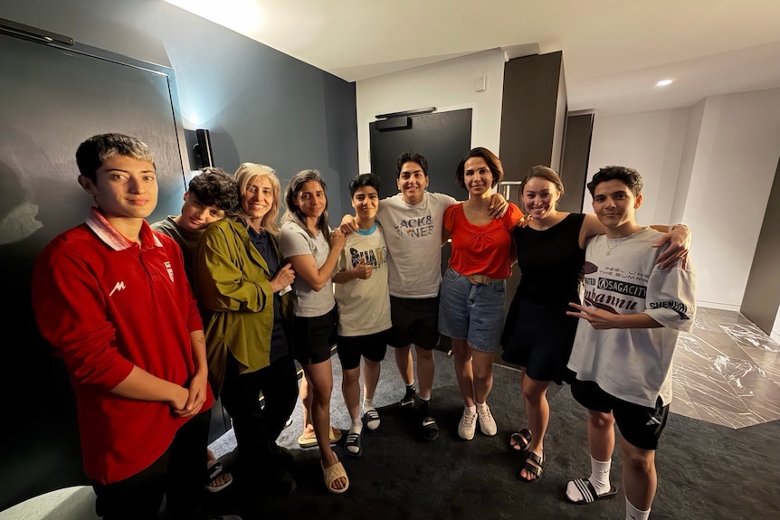 Nine women stand and pose for a photo with arms around each other