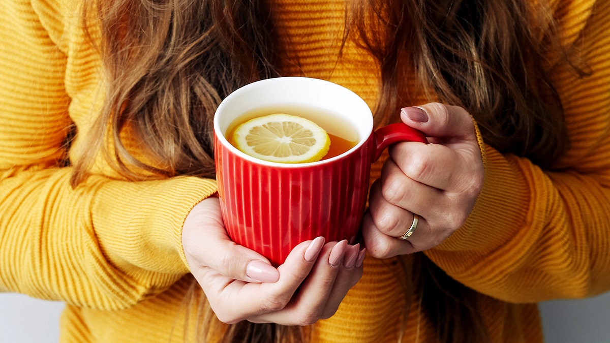 Woman holding mug of hot water with a lemon