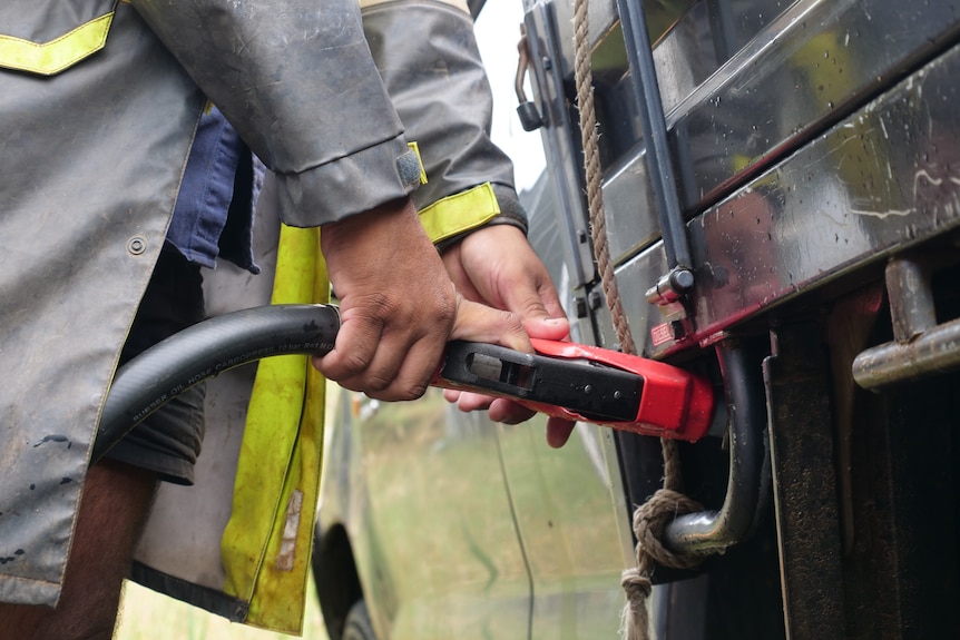 A nman in high vis stands next to a petrol bowser.