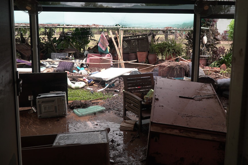 A backyard is filled with damaged items and flooding debris.
