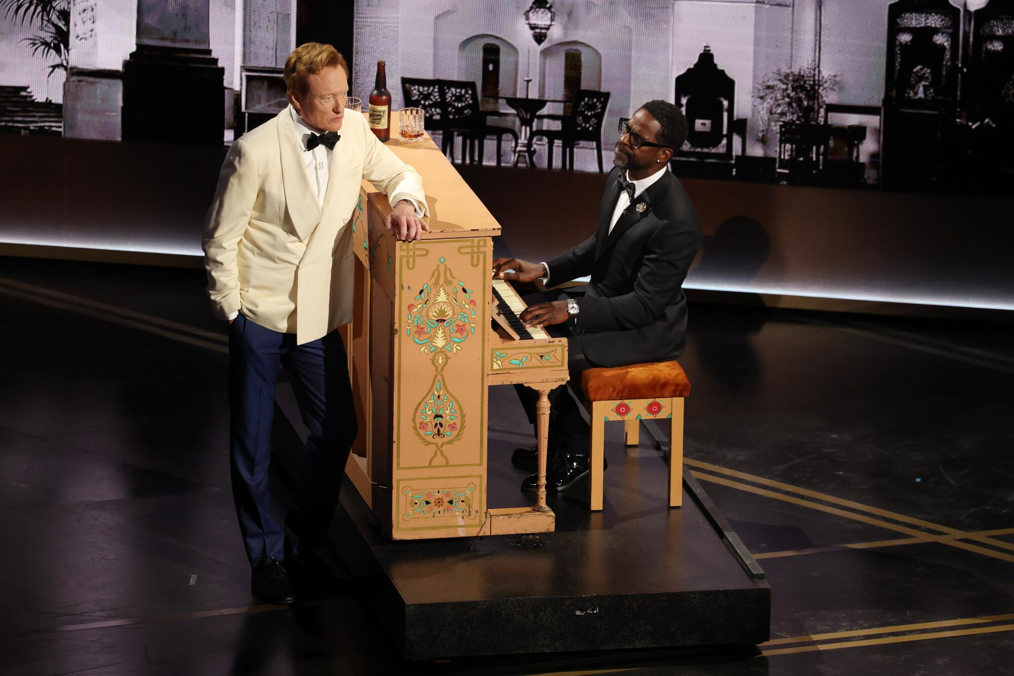  Conan O'Brien wears a white tux jacket and Sterling K. Brown sits at a piano