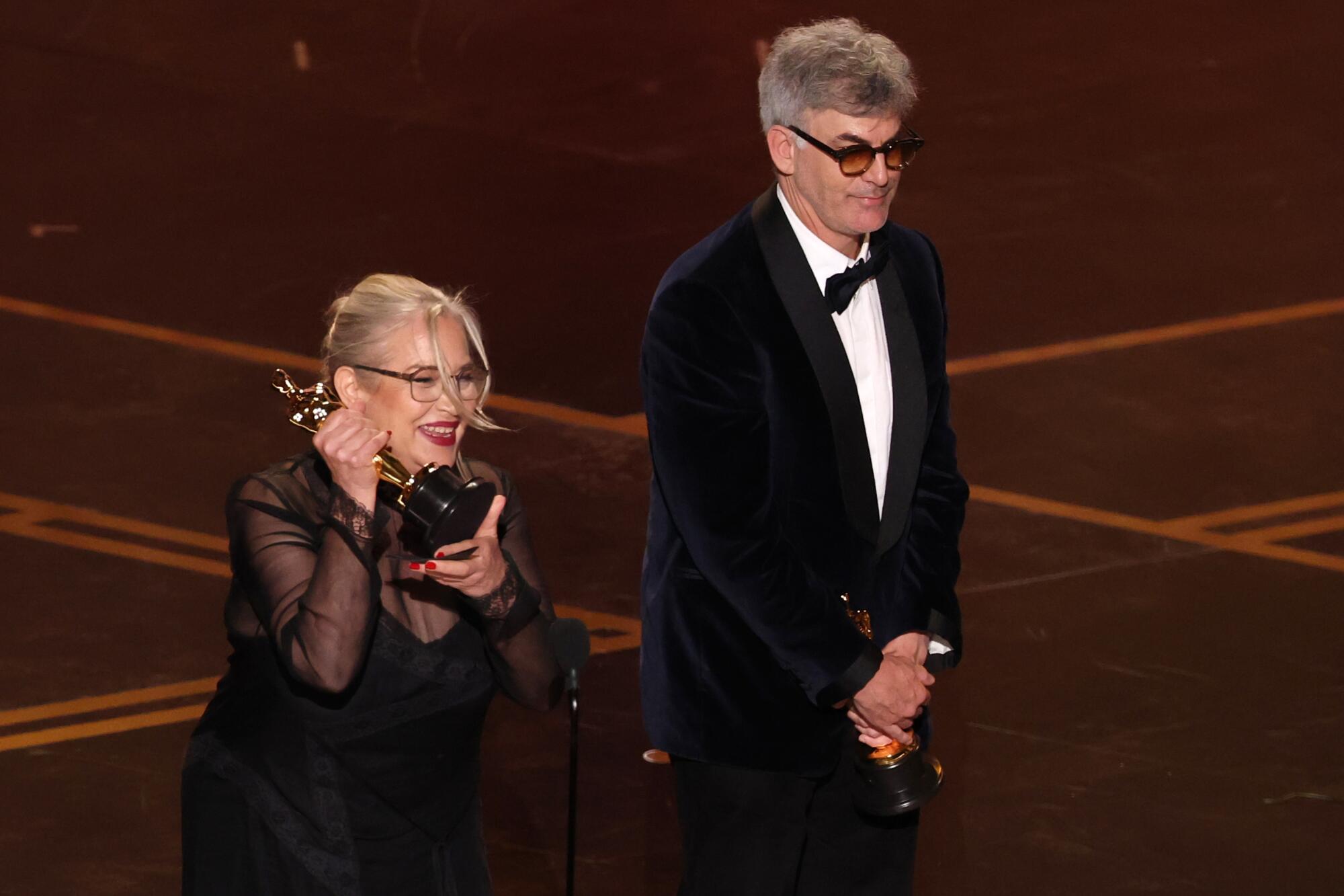 Two people on stage holding an Oscar trophy