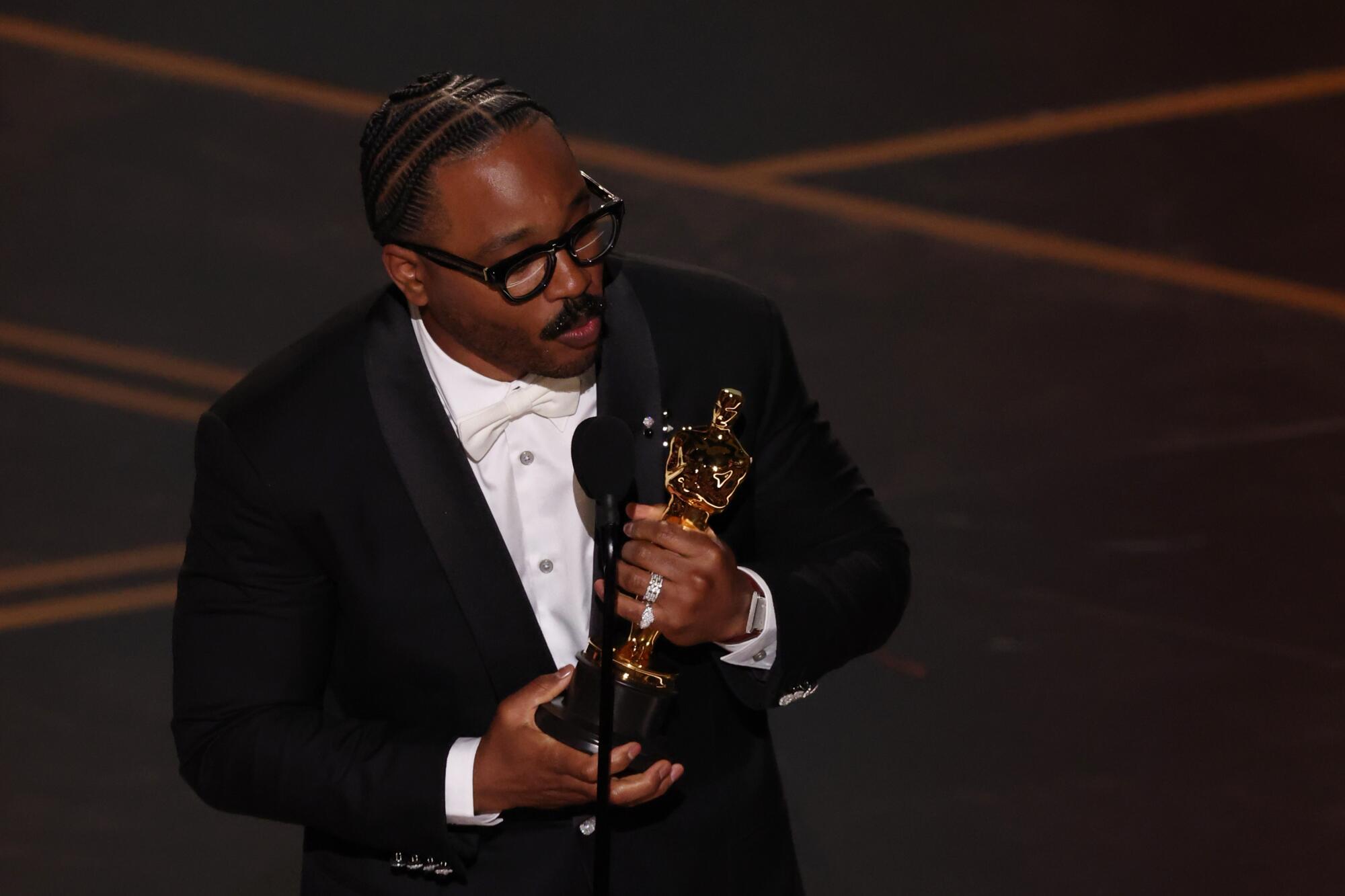 Ryan Coogler holds an Oscar on stage