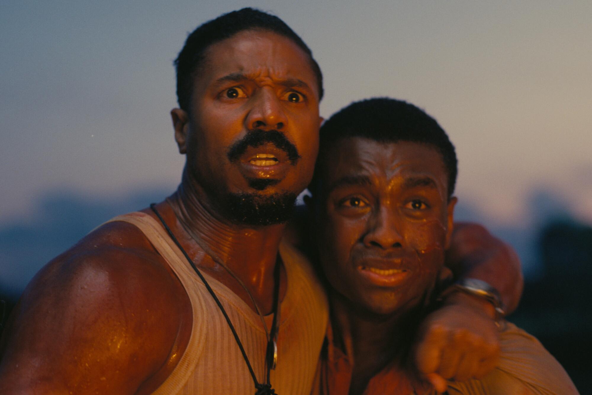 Two men hug each other, alarmed.