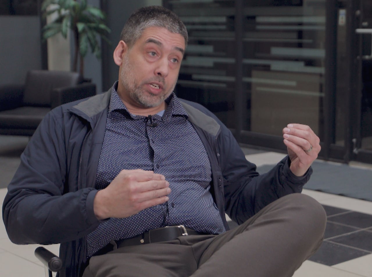 A seated man gestures while speaking.