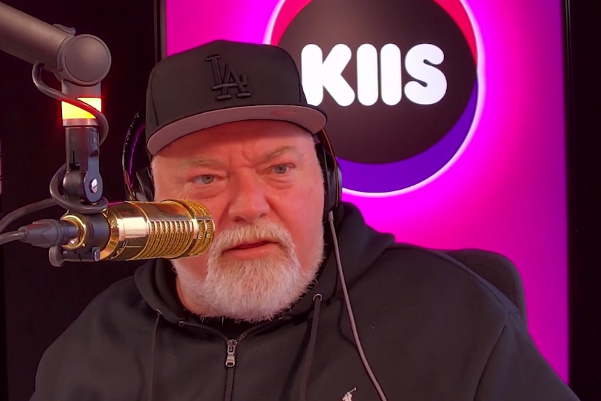 Kyle Sandilands speaks into a gold-coloured microphone in a radio studio.