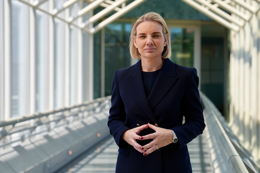 Woman in a navy suit standing on a bridge.