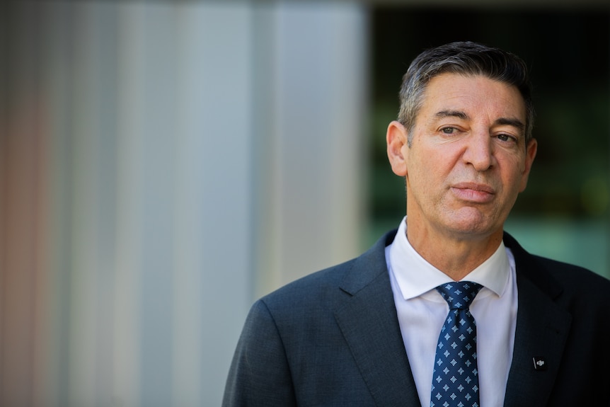 A man in a suit looks straight ahead