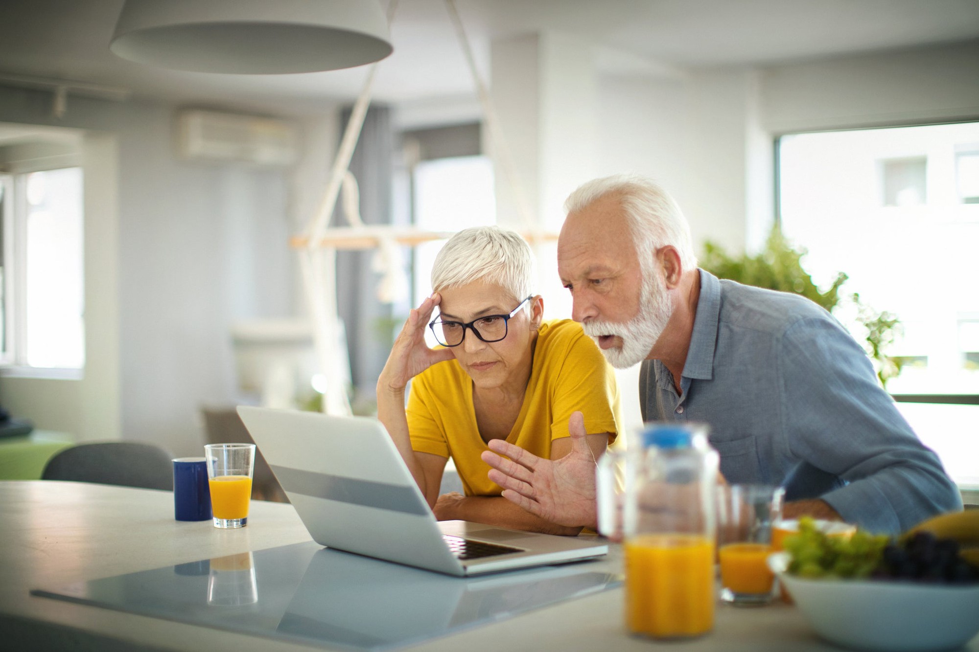 Two people with concerned expressions looking at a laptop.