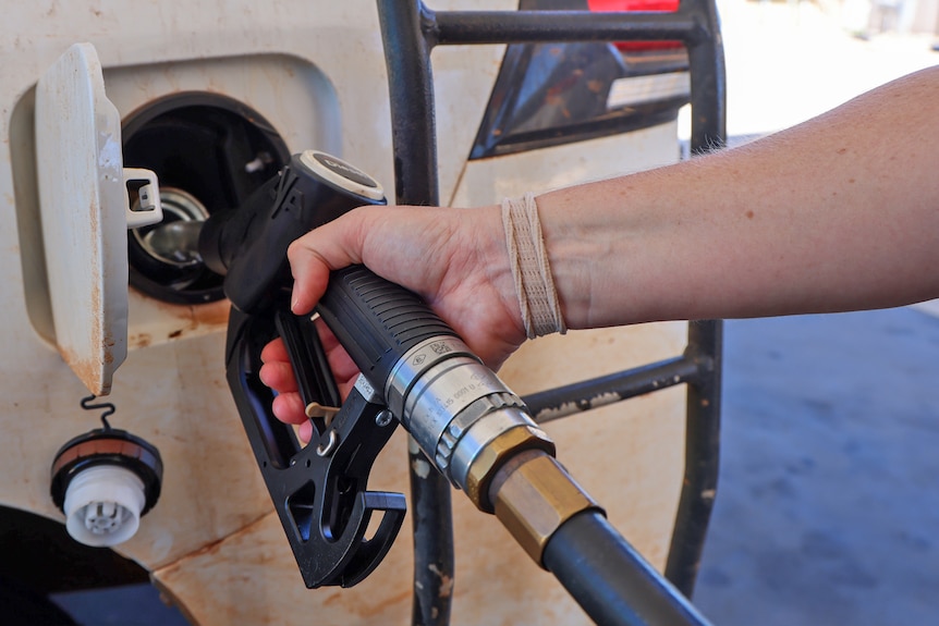 A person fuels up their vehicle at a petrol station close up.
