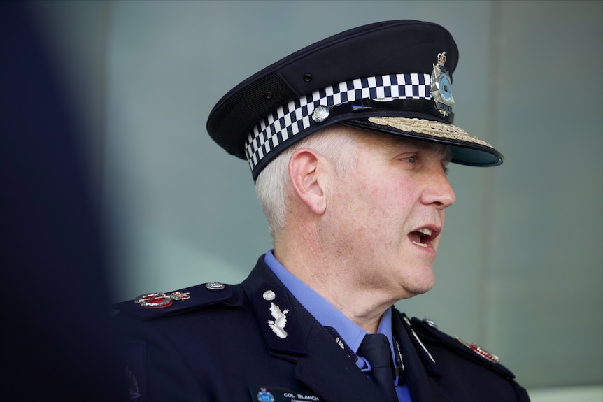 A close-up side-on shot of WA Police Commissioner Col Blanch speaking in his police hat and uniform.