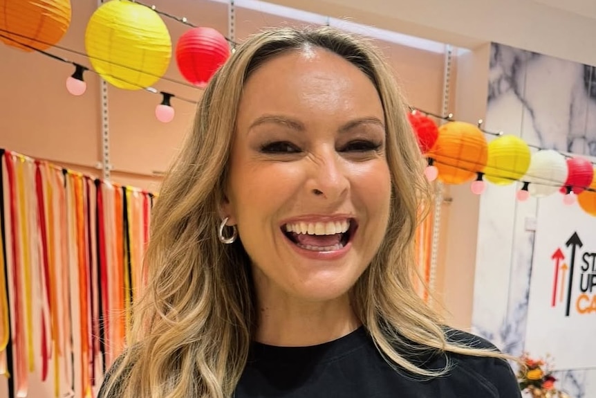 Mel Schilling smiling and wearing a stand up to cancer shirt.