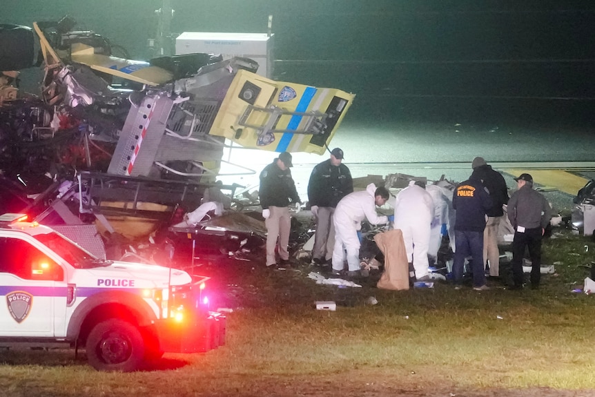 A wreckage of a fire truck with people surrounding it
