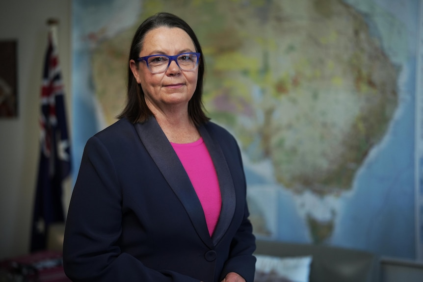A woman standing in front of a map of Australia.