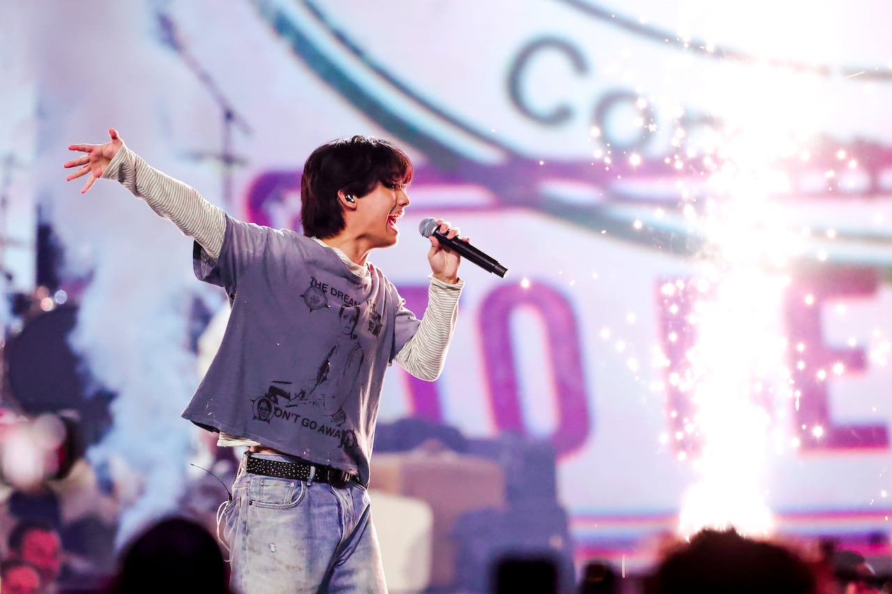 A man holding a microphone sings passionately on a stage.
