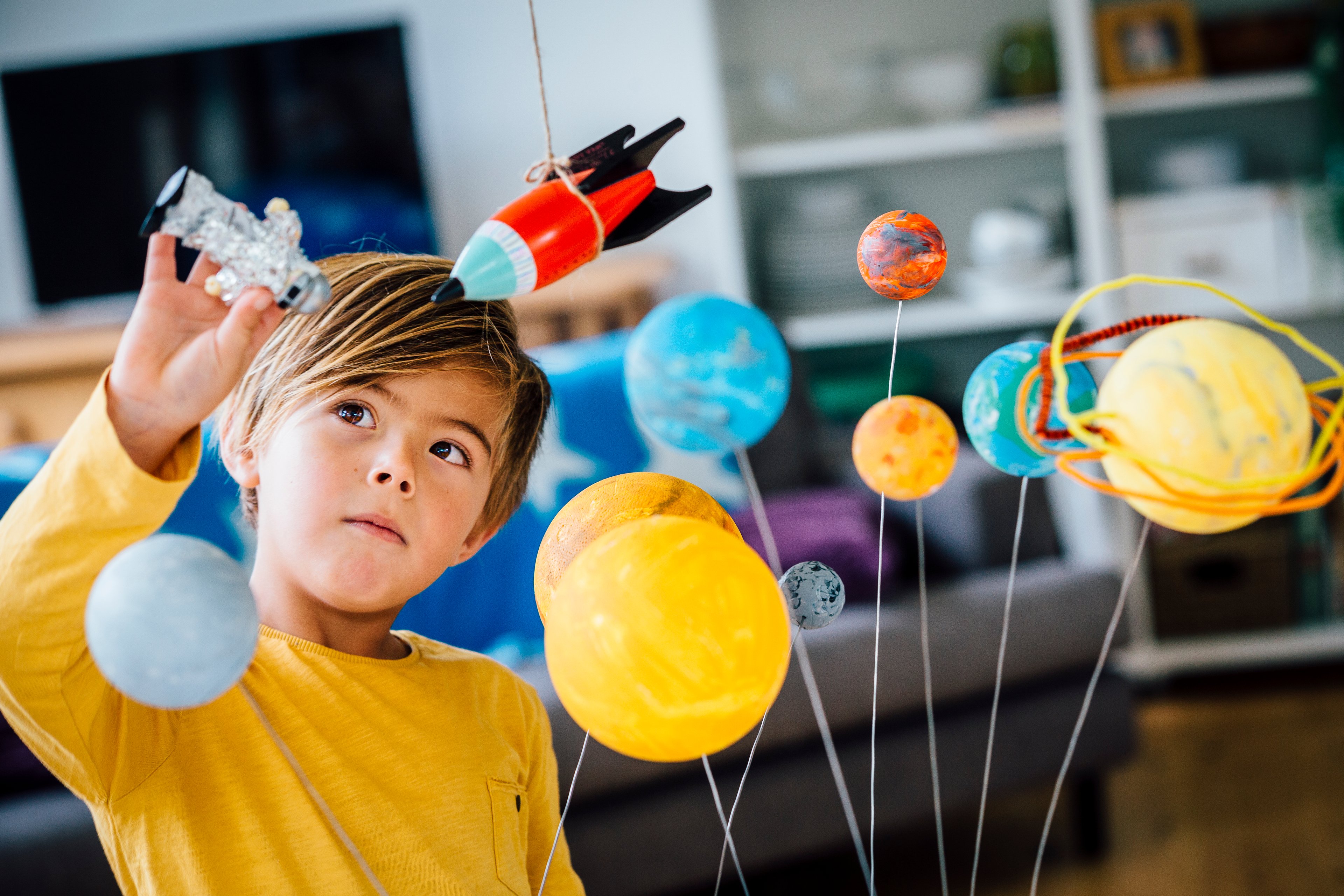 A kid playing with a toy solar system and rockets.
