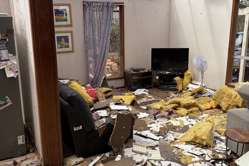 A loungeroom without a roof, scattered with debris.