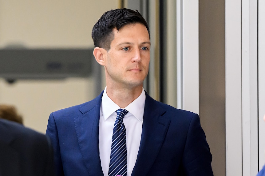 Rory Amon in a navy suit, walking.