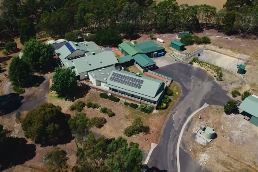 A cluster of buildings ringed by trees from an aerial view.