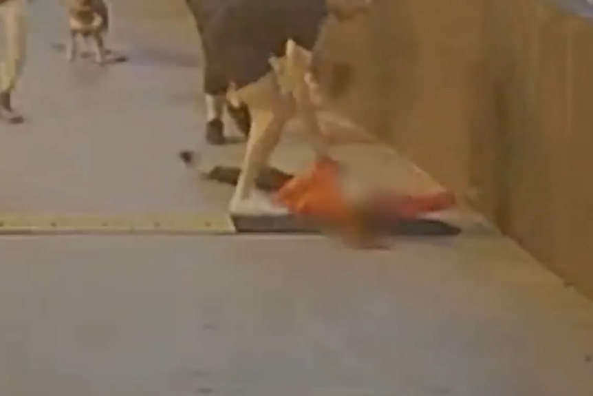 A blurred image of a person on the ground with another person standing over them.