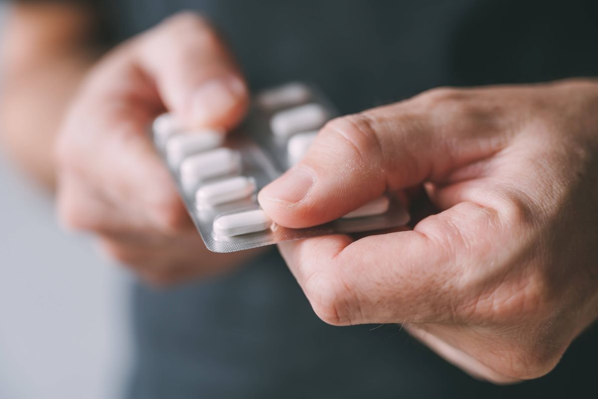 Man taking medicine from blister pack, closeup of hands with selective focus