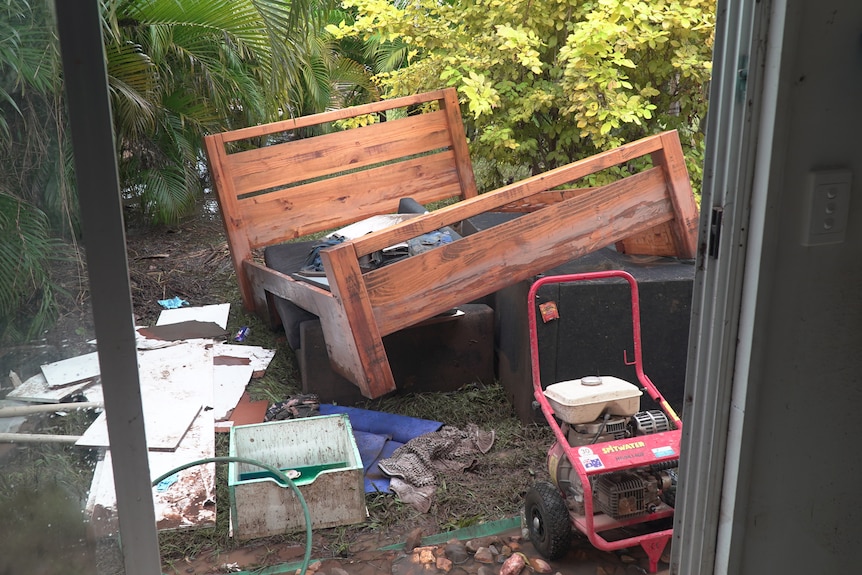 A bed sitting in the yard among other flood-damaged items.