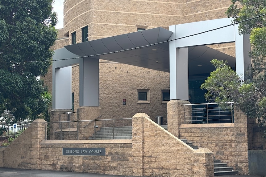 A two or three storey cream brick building with a dual staircase at the front with a sign saying "Geelong law courts".