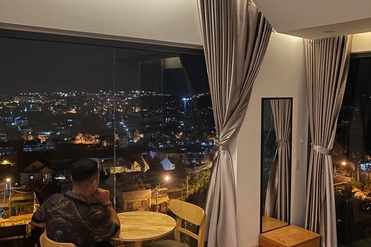 A man stares out at the city lights at night from within a restaurant.