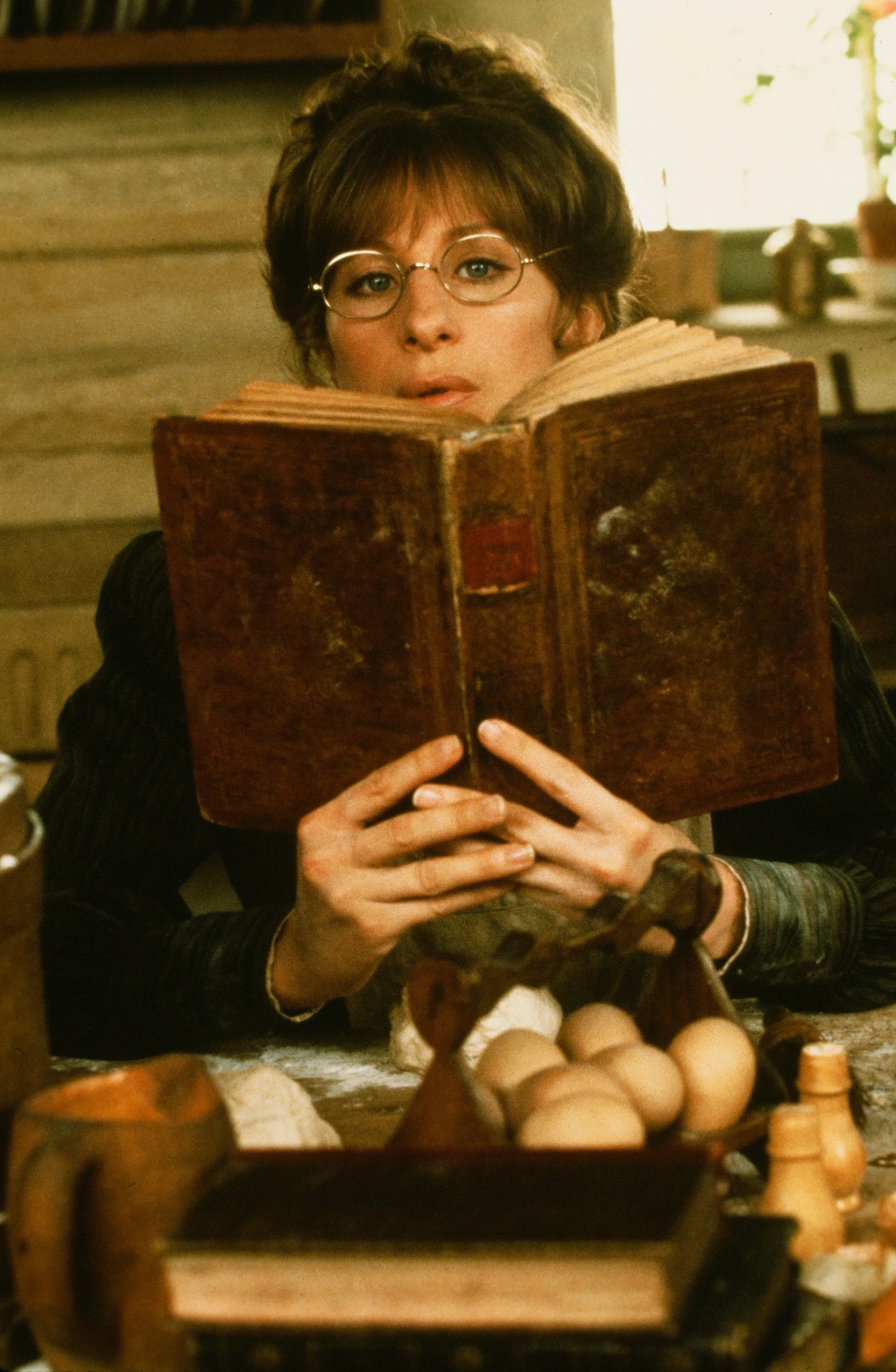 Barbra Streisand as Yentl in the movie "Yentl" looking over a book.