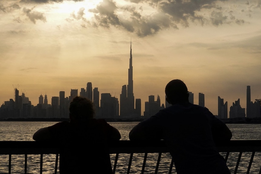 The silhouettes of two people looking at a city skyline.